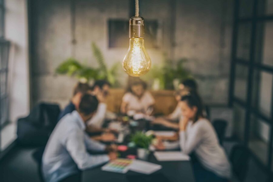 corporate meeting with a lightbulb above in the foreground.